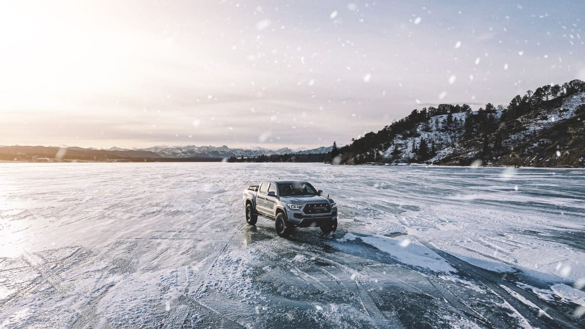 Gray Toyota Tacoma TRD Pro parked on a frozen lake in falling snow
